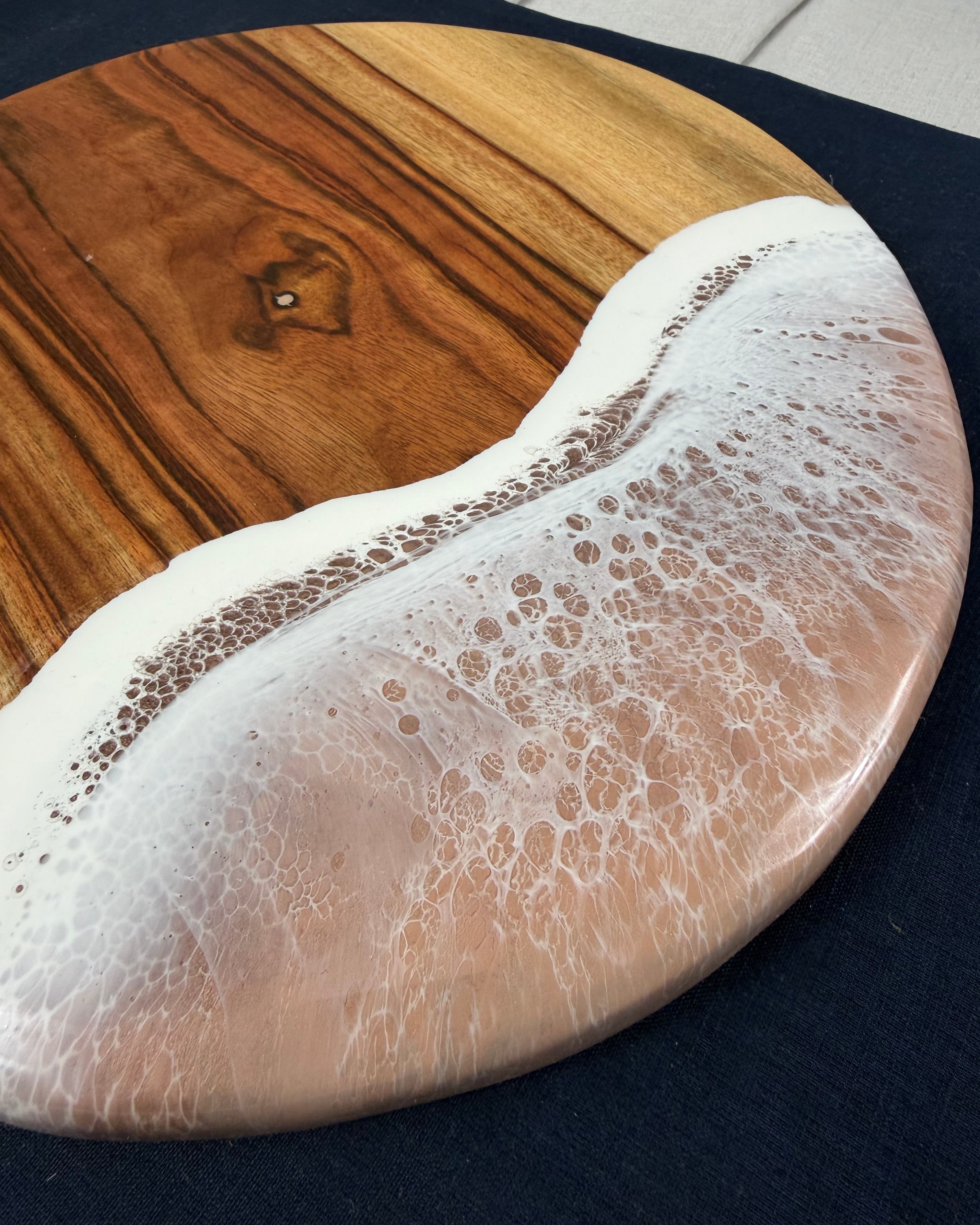 Close-up of beige / neutral  ocean wave resin on square cheeseboard