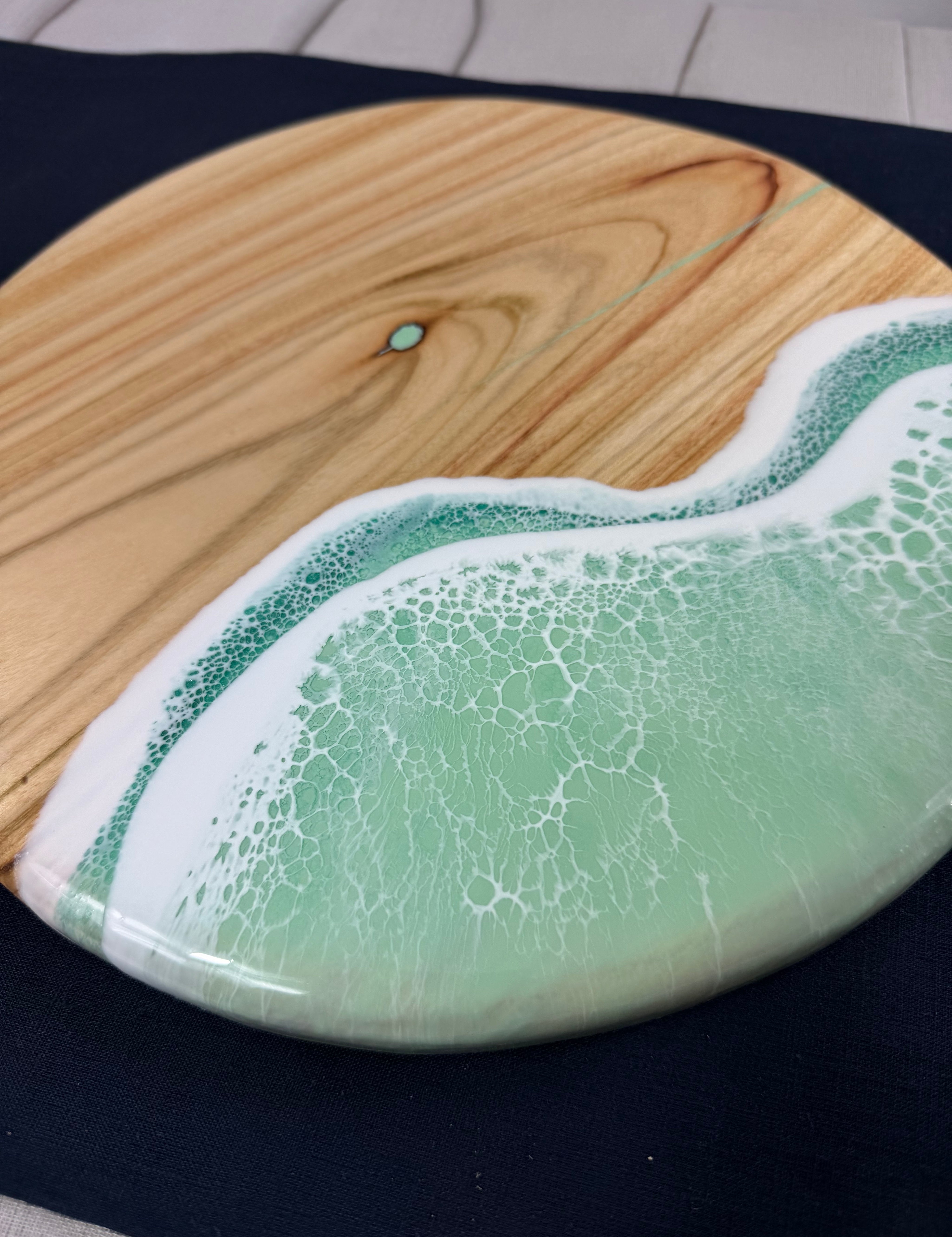 Close-up of mint green ocean wave resin on square cheeseboard