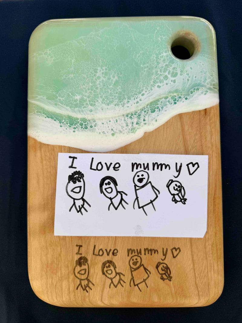 Wooden serving board with ocean resin art and laser engraved child drawing of family and text I Love mummy
