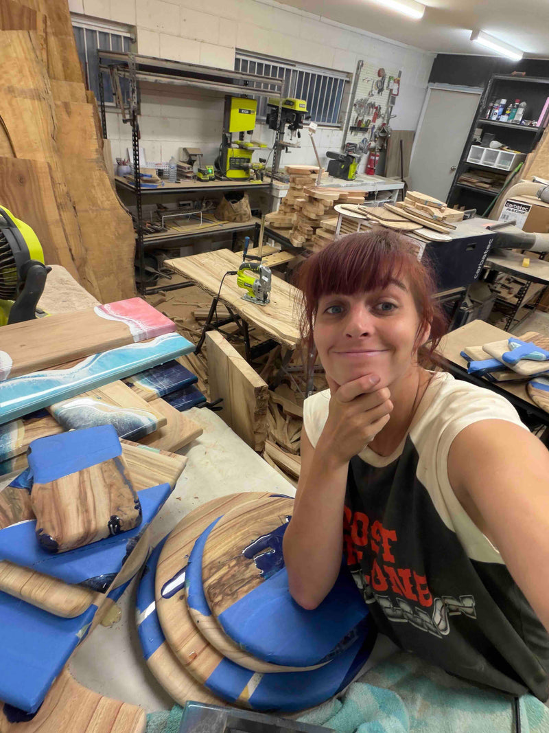 Woman in a woodworking shop surrounded by wood and resin boards