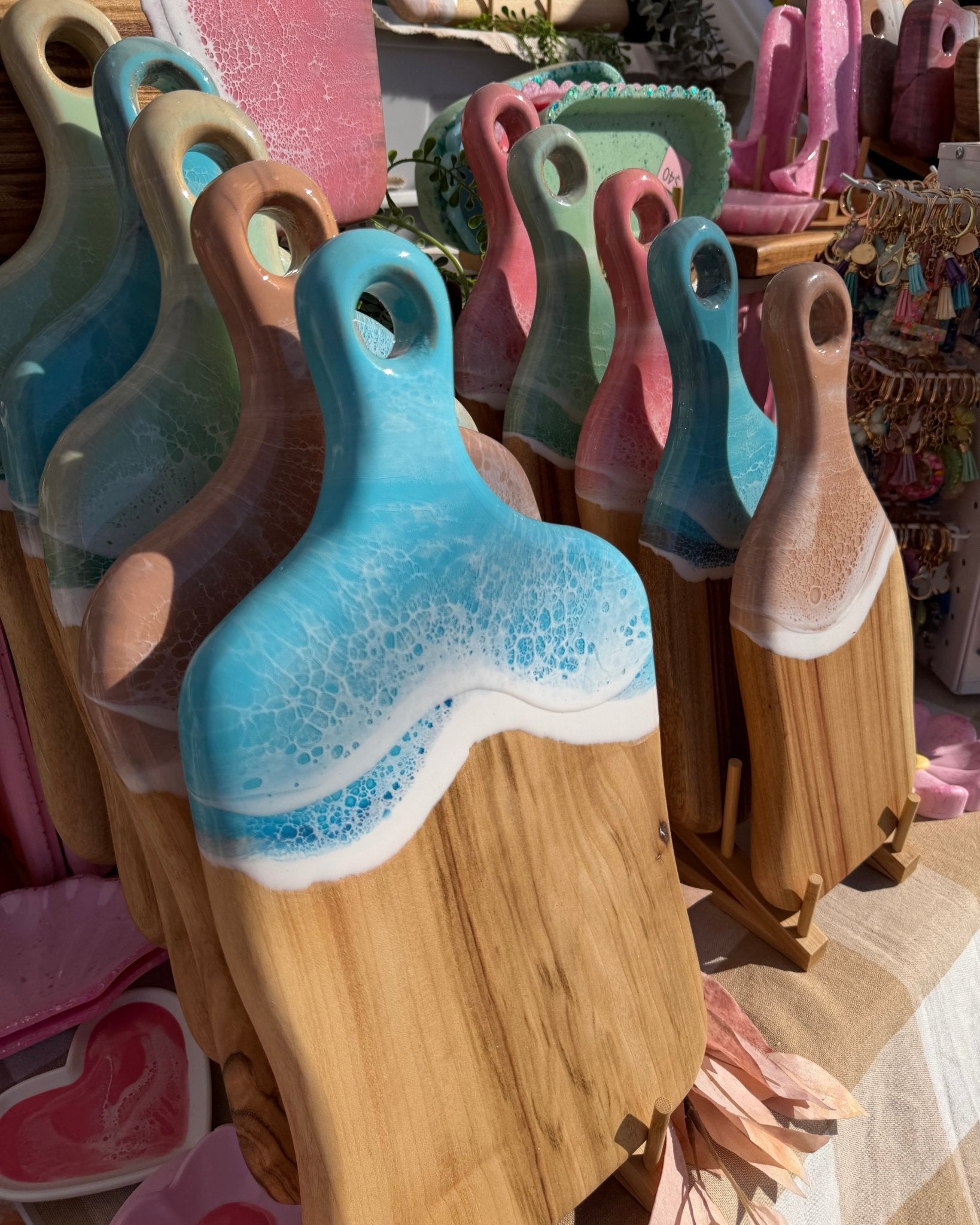 Set of colourful resin cheese boards with handles displayed in tiers at a market