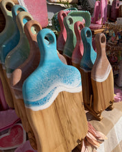 Set of colourful resin cheese boards with handles displayed in tiers at a market