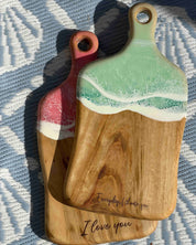 Two wooden cutting boards with high quality resin waves finishes on a textured surface