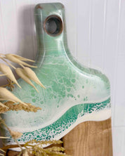 A close up shot of a chopping board with mint ocean resin wave on a white background