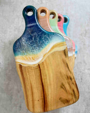 Wooden cutting boards piled on top of each other all positioned at a different angle so you can see each colour. 