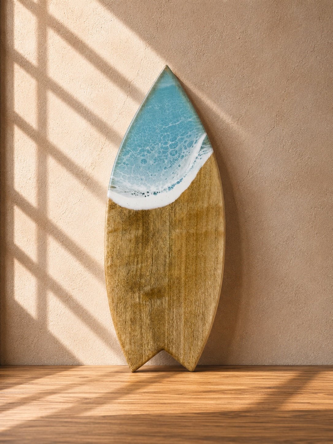 Wooden surfboard-shaped chopping board light blue resin waves on the top leaning on a kitchen wall in natural lighting