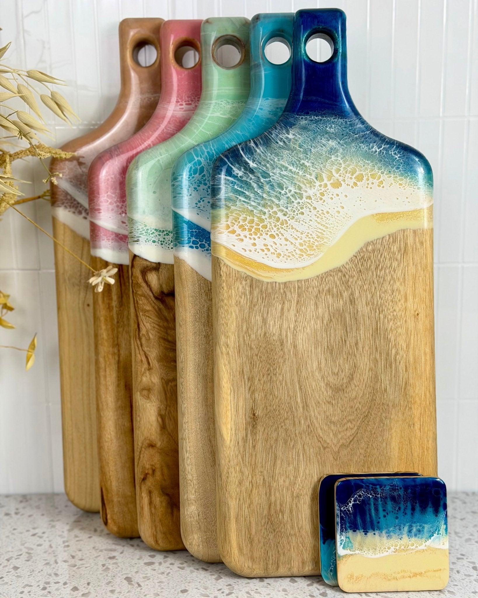 Set of camphor laurel rectangle wooden cutting boards with 5 options of colorful resin on a light background