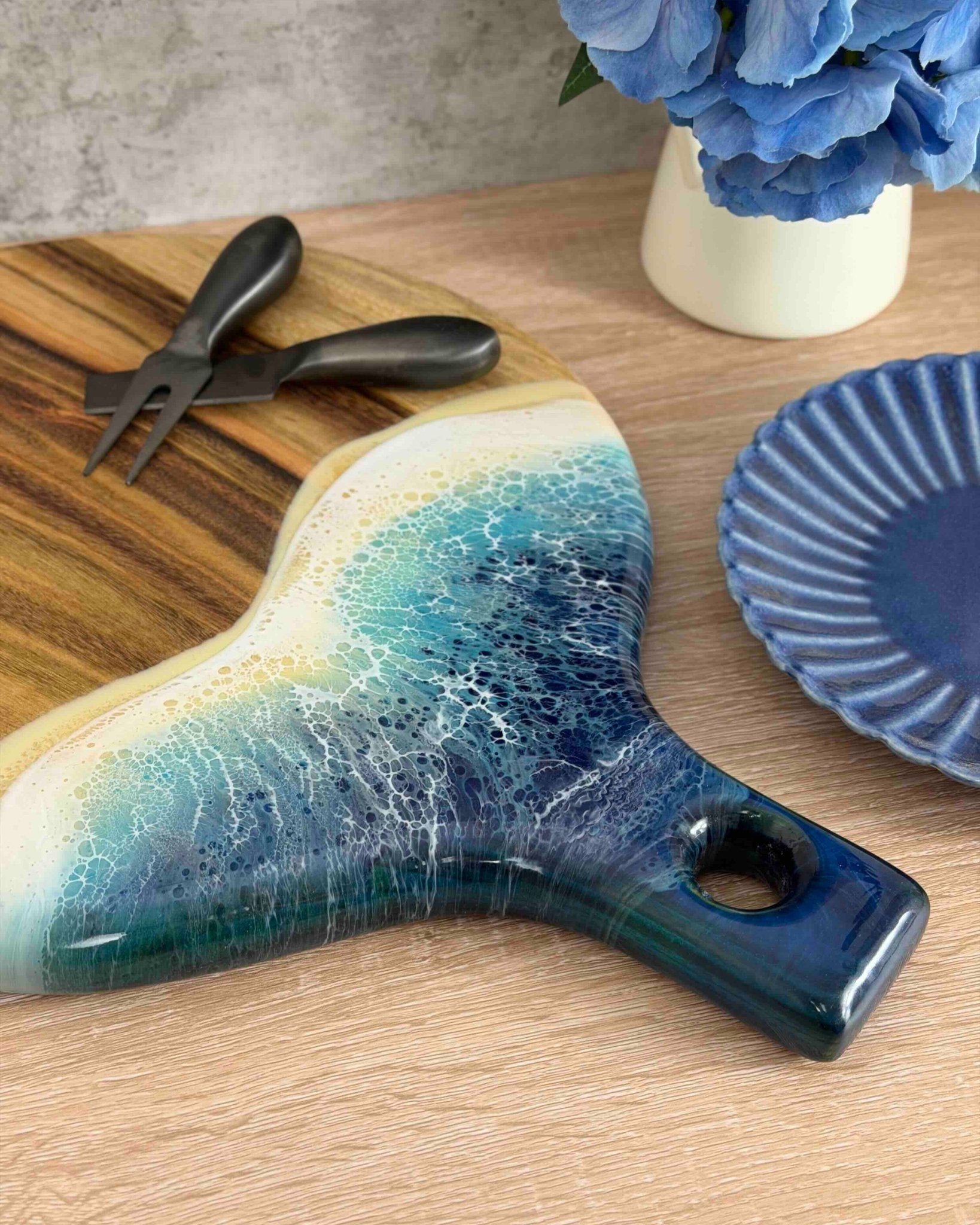 A round paddle board in the beach coloured resin shot on a kitchen table, a close up showing the detail of the resin waves