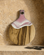 A round paddle board in the pink coloured resin shot in against a kitchen splashback