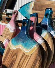 A tiered stacked of round paddle boards in multiple colours being displayed at a market in the sunlight