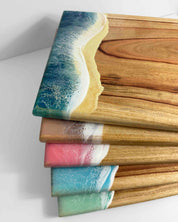 A pile of square resin ocean cheeseboards on a white background