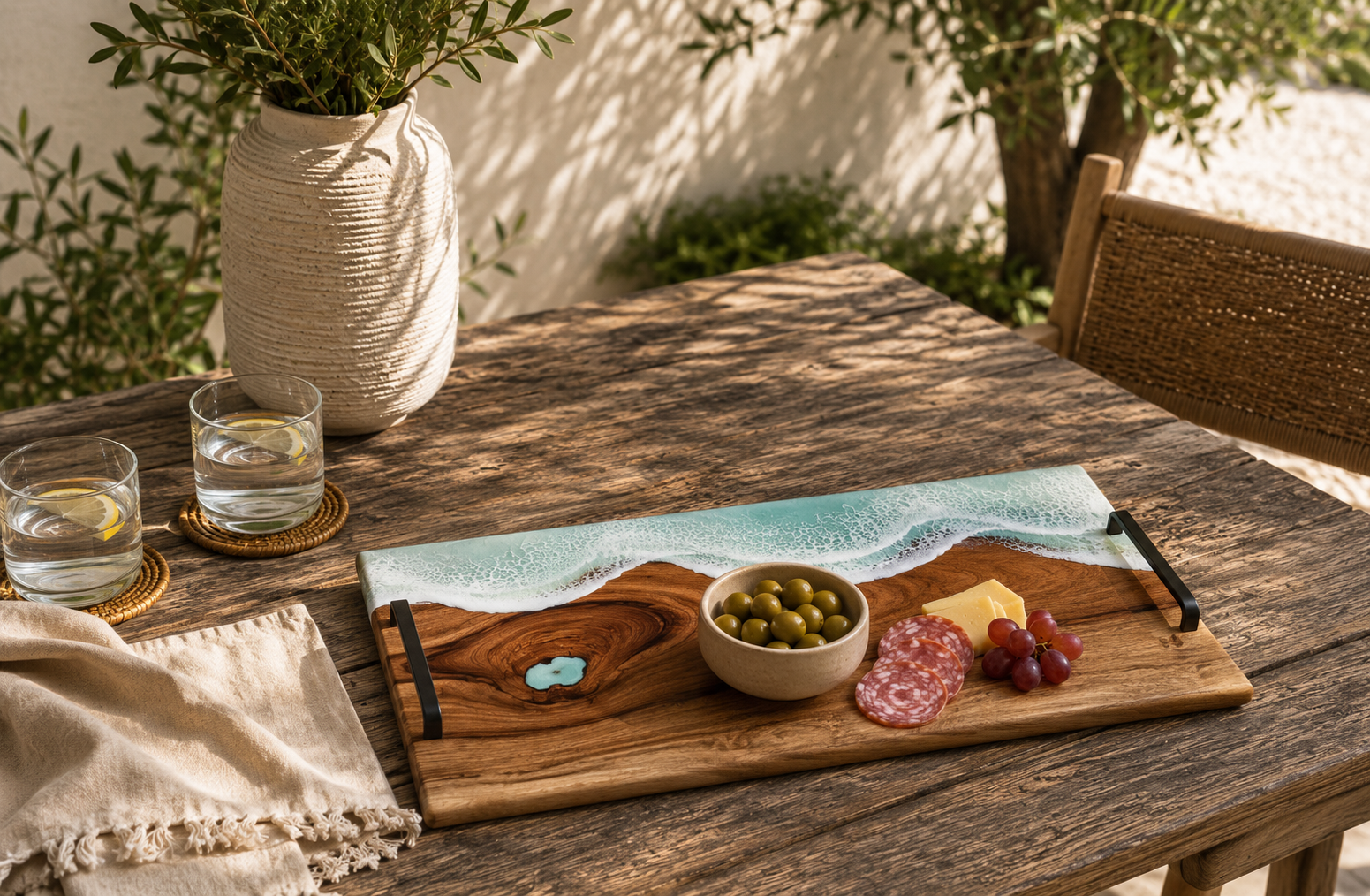 Wooden serving tray with resin ocean art design holding olives cheese and grapes on a rustic outdoor table