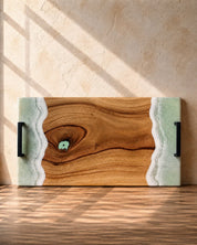 Wooden serving board with mint and white resin waves on the edges on a wooden surface