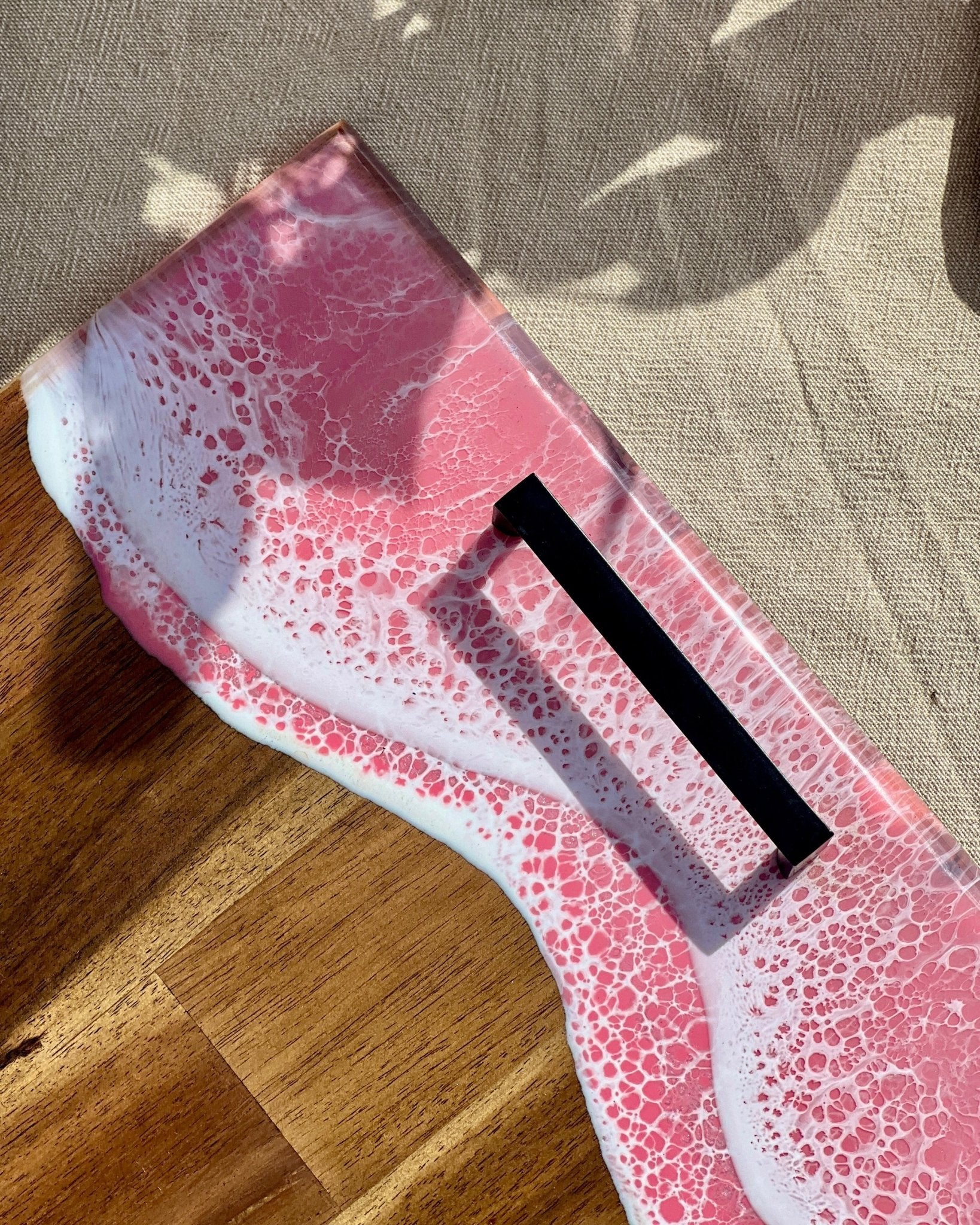 A close up of the pink resin waves on the short edge of the wide handle platters, showing the matte black carry handle